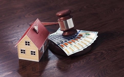 money, model home, and gavel on a desk